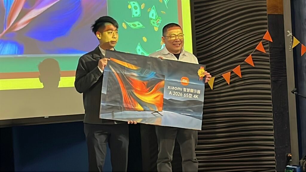 幸運同仁抽中第三獎小米 65 吋智慧顯示器，開心上台合影留念